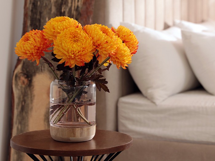 Bedside table with a vase of orange flowers.